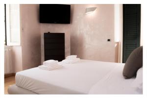 a bed with white sheets and a tv on the wall at Ostia Holiday La Marina in Lido di Ostia