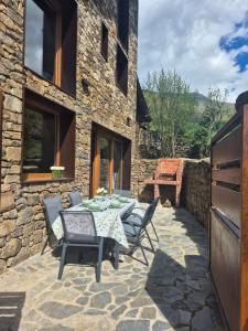 a patio with a table and chairs in front of a stone building at La era de Somaniezo in Luriezo