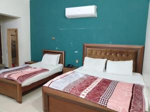 a bedroom with two beds and a blue wall at New Era Guest House And Hotel in Multan