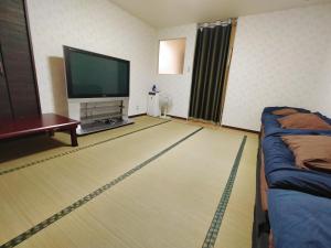 a living room with a flat screen tv and a couch at SECRET BASE Station Side in Osaka