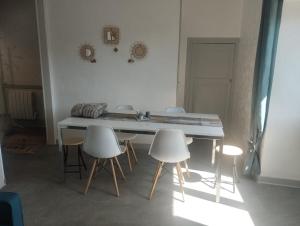 a kitchen with a table and white chairs at Maison de ville centrale in Vierzon