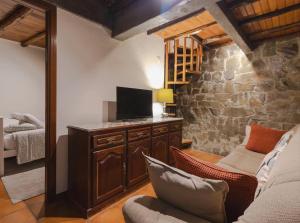 a living room with a tv and a stone wall at BABhouse Lagar Antigo - Coração do Douro in Nagoselo do Douro