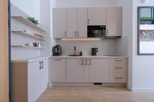 a white kitchen with white cabinets and a microwave at Laguna Beskidów Resort - Apartament E59 in Zarzecze +7 photos