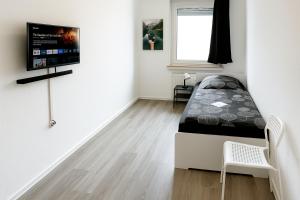 ゾーリンゲンにあるVAZ Apartments Birkenweiher für Monteure und Fachkräfte, WLAN,TV, Küche, 4-8 Personenの壁にテレビとベッドが備わる客室です。