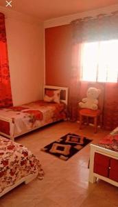 a bedroom with two beds and a teddy bear on a chair at Dar yess in Bin Rhilouf