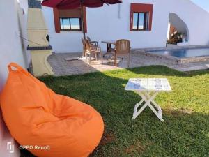 an orange bean bag chair and a table in a yard at Dar yess in Bin Rhilouf +8 photos
