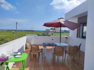 a patio with a table and chairs and an umbrella at Dar yess in Bin Rhilouf