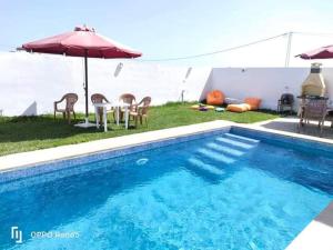 a swimming pool with a table and an umbrella at Dar yess in Bin Rhilouf