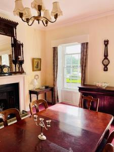 a dining room with a wooden table and a fireplace at Kilmartin House - Georgian House on Private Estate and Farm in Greystones