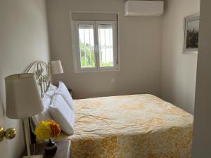 een bed in een witte kamer met een raam bij De la Danza in Sevilla