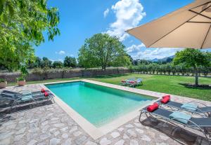 ein Swimmingpool mit zwei Stühlen und einem Sonnenschirm in der Unterkunft Villa Vinya Frares - Luxury Retreat in Pollença