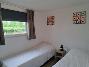 ein Schlafzimmer mit zwei Betten und einem Fenster in der Unterkunft Chalet Hart van Zeeland met overdekt terras & natuur VP086 in Heinkensand + 30 Fotos