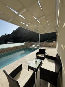 a patio with a table and chairs next to a swimming pool at Villa Casa Solea in Mírthios
