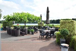 eine Terrasse mit Tischen und Stühlen und einem Sonnenschirm in der Unterkunft Chalet Hart van Zeeland met overdekt terras & natuur VP086 in Heinkensand
