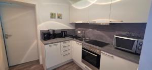 a kitchen with white cabinets and a sink and a microwave at Ferienwohnung Schlossblick in Kippenheim