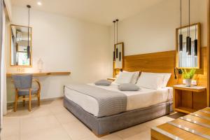 a bedroom with a large bed and a chair at Skopelos Holidays Hotel & Spa in Skopelos Town
