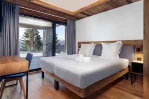 ein Schlafzimmer mit Bett, Schreibtisch und Fenster in der Unterkunft Madame Vacances Résidence L'Orée du Bois in La Rosière