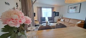 ein Wohnzimmer mit einem Tisch mit einer Vase mit rosa Blumen in der Unterkunft Chalet Hart van Zeeland met overdekt terras & natuur VP086 in Heinkensand