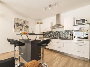 una cucina con mobili bianchi e sgabelli da bar di Spacious apartment with mountain view a Bad Gastein