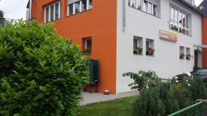 ein orangefarbenes und weißes Gebäude mit Blumen in den Fenstern in der Unterkunft Hotel Mila in Reichenbach an der Fils