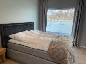 una cama en una habitación con una ventana grande en Eksklusiv leilighet med spektakulær utsikt, en Kabelvåg