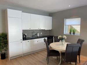 Una cocina con gabinetes blancos y una mesa con sillas. en Eksklusiv leilighet med spektakulær utsikt, en Kabelvåg 10 fotos más