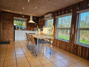 a kitchen with a table and chairs and windows at Jagthytten in Randbøldal