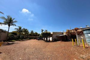 a dirt road in front of a building with palm trees at Hotel Primavera in Aramina