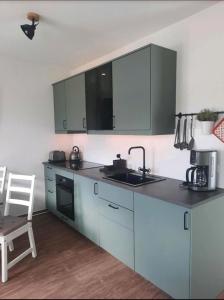 a kitchen with blue cabinets and a sink and a chair at Küstenwind in Graal-Müritz