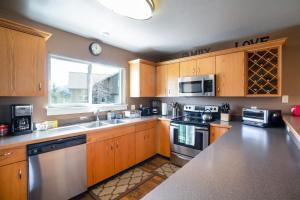 a kitchen with wooden cabinets and stainless steel appliances at 3BR Big Sky Getaway with Hot Tub and Mountain Views in Big Sky
