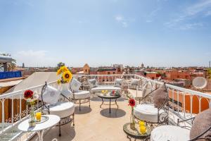 a balcony with tables and chairs and a view of the city at RIAD AWINATI Location Privatisée , Piscine a jets, Petit déjeuner et magnifique Rooftop avec vue a 360 in Marrakesh +49 photos