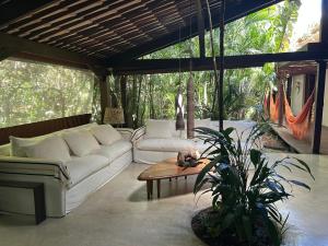 ein Wohnzimmer mit einer weißen Couch und einem Tisch in der Unterkunft Maravilhosa Casa Praia de Santo Andre Bahia in Santo André