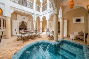 an indoor pool in a mansion with a table and chairs at RIAD AWINATI Location Privatisée , Piscine a jets, Petit déjeuner et magnifique Rooftop avec vue a 360 in Marrakesh