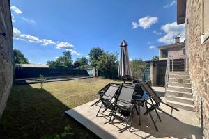 un tavolo, sedie e un ombrellone in un patio di Villa Platon - Jaccuzi - JardinTerrassePétanque a Brive-la-Gaillarde