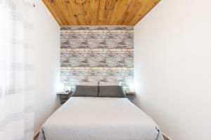 a bed in a room with a brick wall at Home2Book Serene Stay & Sea View Terrace in Arico in La Mareta +11 photos