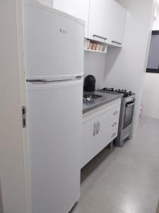 a white kitchen with a refrigerator and a stove at lindo apartamento martim de sá 2 dormitórios wi fi piscina pé na areia 32 b in Caraguatatuba