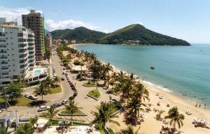 a view of a beach with palm trees and the ocean at lindo apartamento martim de sá 2 dormitórios wi fi piscina pé na areia 32 b in Caraguatatuba