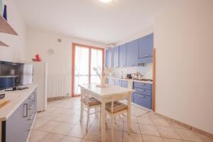 Una cocina con gabinetes azules y una mesa blanca. en Residence Le Ginestre Mare, en Cavallino-Treporti