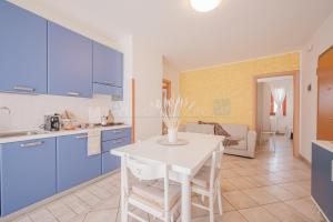 Una cocina con gabinetes azules y una mesa blanca. en Residence Le Ginestre Mare, en Cavallino-Treporti