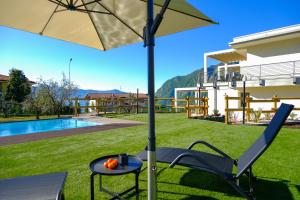 een tafel en stoel onder een parasol naast een zwembad bij Costa Blu - Pool and terrace overlooking the lake in Riva di Solto