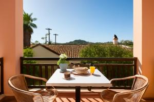 a table with a plate of food on a balcony at Veneti Apartments - Corfu Serene Getaways in Sidari