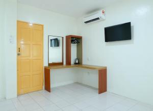 a room with a desk and a television on a wall at Mersing Hotel in Mersing