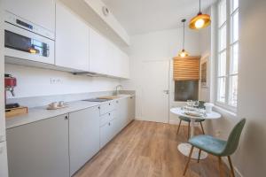 a kitchen with white cabinets and a table with a blue chair at Villa Victor Hugo by Odomo in Avignon