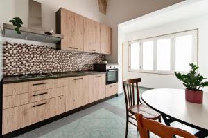 a kitchen with wooden cabinets and a table with chairs at Sardinia 10 Apartment - Lecce Selection in Lecce