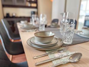 a wooden table with a bowl and plates and silverware at MaBu Homes - Mitten in Nienburg in Nienburg