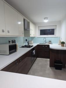 a kitchen with white cabinets and a microwave at South Shields Executive Apartment in South Shields