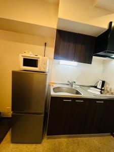a kitchen with a microwave on top of a refrigerator at Leopard Shinsaibashi 心斎橋 505 in Osaka