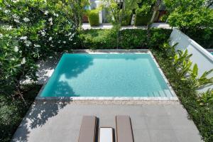 a swimming pool with two lounge chairs in a garden at Argo Pattaya Resort and Villas in Ban Huai Yai