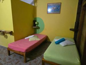 two beds in a room with yellow and green at Bungalow cosy à Goyave avec vue sur le jardin in Goyave