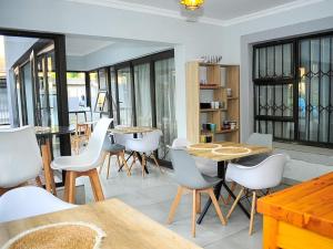 a dining room with wooden tables and white chairs at 5@Partridge Guesthouse in Newcastle